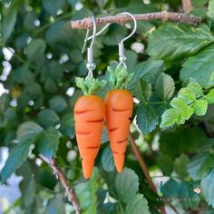 two carrot shaped earrings hanging from a tree branch