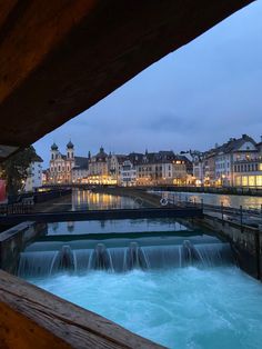 a river running through a city with buildings in the background at night and water rushing under it