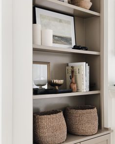 two baskets sit on top of a shelf in a room with books and other items