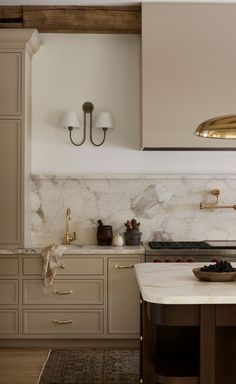 a kitchen with marble counter tops and gold accents on the cabinets, along with brass fixtures