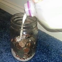 a person pouring milk into a jar filled with coins on blue carpeted flooring