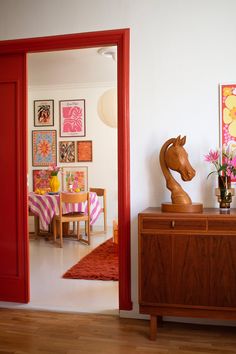 a living room with a horse statue on top of a wooden dresser next to a red door