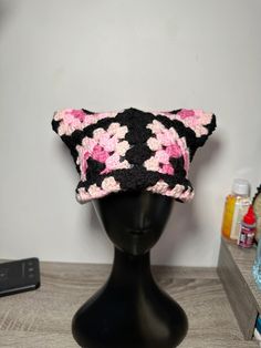 a black hat with pink flowers on it sitting on top of a mannequin head