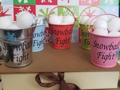 four buckets filled with snowballs on top of a wooden table next to a ribbon