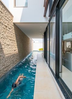 a person swimming in a pool next to a building