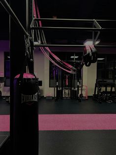 a gym with pink and black flooring, punching bag and exercise equipment in the background