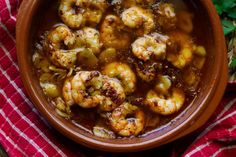 a bowl filled with shrimp and vegetables on top of a red and white checkered cloth