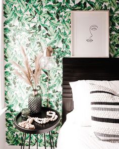 a bedroom with green leaves on the wall and a black table in front of it