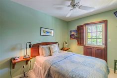 a bedroom with green walls and a bed in the corner, along with a ceiling fan