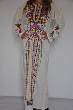 "This beautiful Vintage Kaftan Maxi dress is 100% Bedouin hand embroidered. It is the perfect dress for your summer party or night out. This dress is hand stitched by a group of 3 girls in Siwa Egypt, and takes around four weeks to make. This dress is literally a piece of art with the quality, colourfulness, and design of the embroidery. IMPORTANT NOTE : This dress is Vintage and is made by a group of girls working on it over a long period of time, and thus there might be some very minor imperfe White Cotton Kurta With Geometric Embroidery, Traditional Cotton V-neck Dress, Bohemian Embroidered Maxi Dress For Traditional Ceremonies, Traditional Patterned Dresses For Summer Ceremonies, Summer Dresses With Traditional Patterns For Ceremonies, Bohemian Dresses With Geometric Embroidery For Traditional Ceremonies, Bohemian Maxi Dress For Traditional Ceremonies, White Dress With Traditional Patterns For Spring, White Dresses With Traditional Patterns For Spring