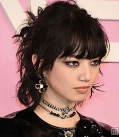 a close up of a person with black hair and piercings on her head wearing necklaces