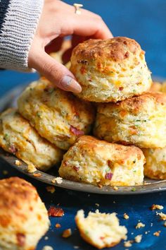 a person picking up some biscuits from a plate on a table with other food items