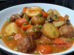 a white bowl filled with meat and veggies on top of a black table