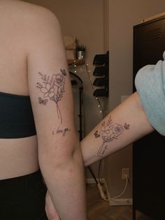 two women with matching tattoos on their arms