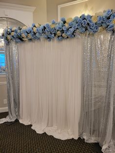 a white backdrop with blue flowers and sequins on the side, along with sheer drapes