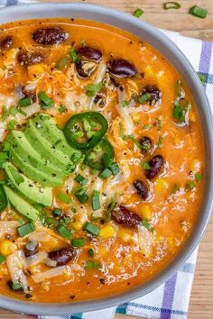 a bowl of mexican soup with tortilla, beans and avocado