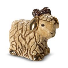 a golden sheep figurine sitting on top of a white surface