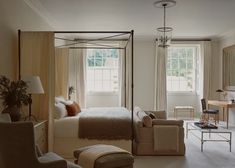 a bedroom with a four poster bed sitting next to a living room table and chairs