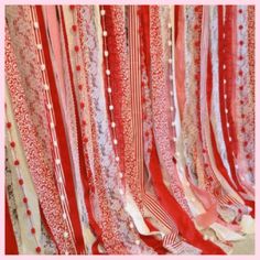 some red and white ribbons hanging from the ceiling in front of a wall with flowers on it