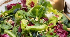 a salad with lettuce, pomegranate and nuts in it on a plate