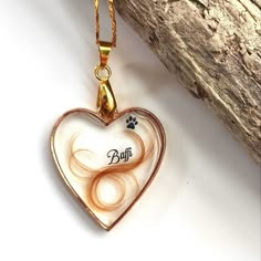 a heart shaped glass pendant with an animal's paw on it