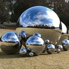 a group of shiny balls sitting on top of a grass covered field next to trees