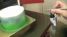 a person is cutting a green and white cake with a sharpie knife on a table