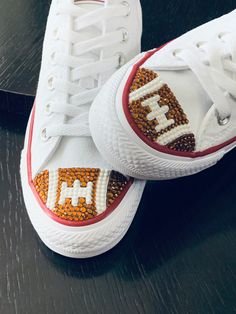 two white shoes with red and yellow beading on the bottom, one has an e