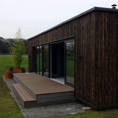 a small wooden house sitting on top of a grass covered field next to a lush green field