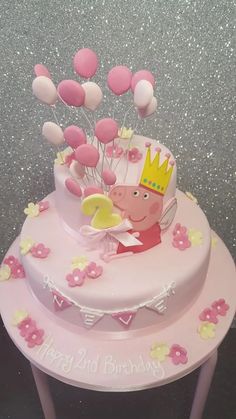 a pink cake with balloons and a peppa pig on top