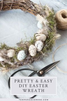 an easter wreath with eggs and moss on it next to some twine spools