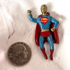 a coin is laying next to a small figurine with a superman figure on it