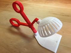 a pair of red scissors sitting on top of a wooden table next to a grater