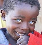 a young boy with blue eyes smiles for the camera while wearing a red and blue jacket