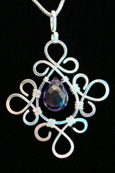 a necklace with an intricate design and a purple stone in the center on a black background