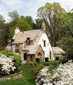 a white house surrounded by trees and flowers