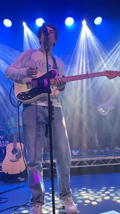 a man standing on top of a stage holding a guitar