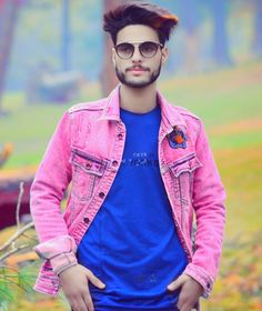 a young man in a pink jacket and blue t - shirt is posing for the camera