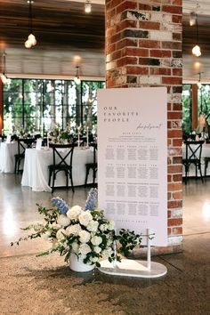 a table with white flowers and greenery is set up in front of a brick pillar