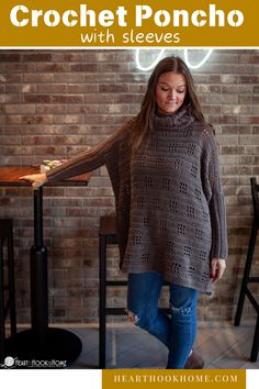 a woman standing in front of a brick wall wearing a crochet poncho with sleeves