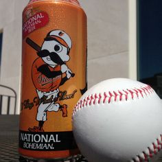 a can of beer and a baseball on a table