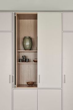 a white cabinet with some vases on top and other items in the bottom shelf