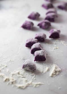 purple and white powdered dough on a counter with other ingredients scattered around it in the foreground