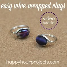 two rings sitting on top of a brown table next to each other, one with a purple glass bead in the middle