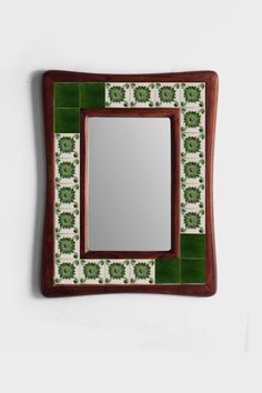 a mirror mounted to the side of a wall next to a green tiled flooring