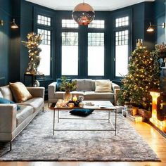 a living room decorated for christmas with blue walls and lights on the windowsills