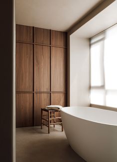 a large white bathtub sitting next to a window in a room with wooden walls