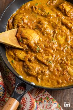 a pan filled with meat and sauce on top of a wooden table