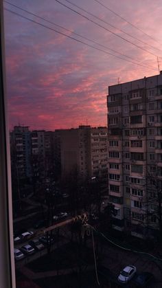 the sun is setting over some buildings and cars