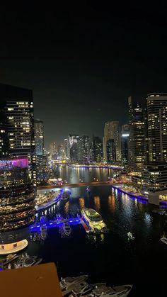 an aerial view of the city at night with boats in the water and buildings lit up